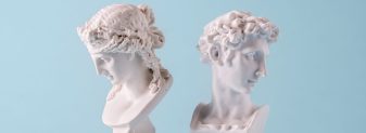 Two small antique style Roman or Grecian busts of young men facing away from each other on blue